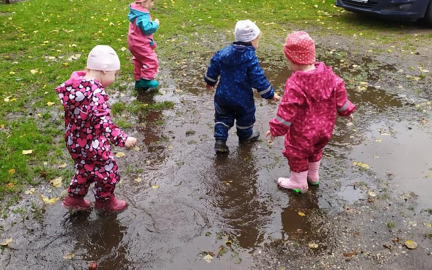 Bewegung und Natur, Kinder in Matschhosen planschen draußen in der Pfütze