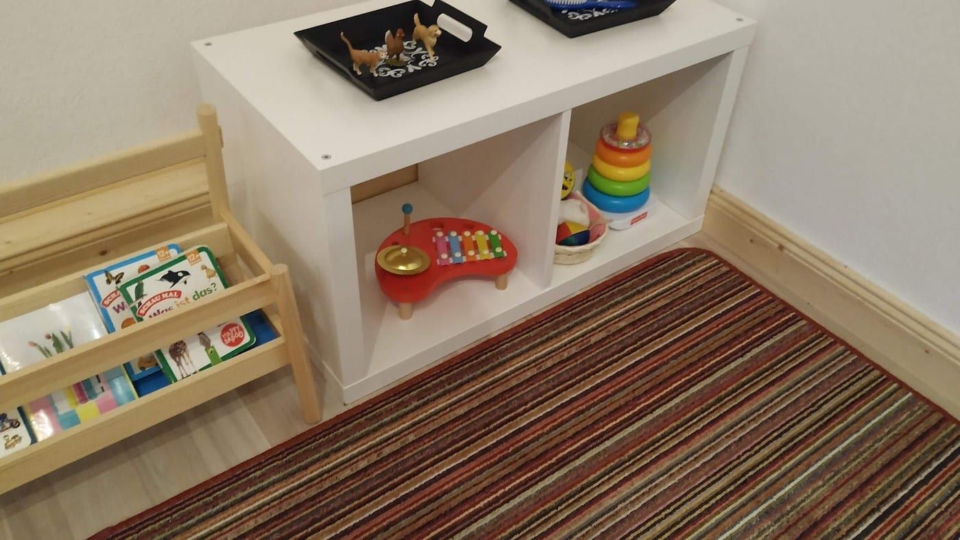 Holzregal mit Spielzeug und Bilderbüchern im Gruppenraum