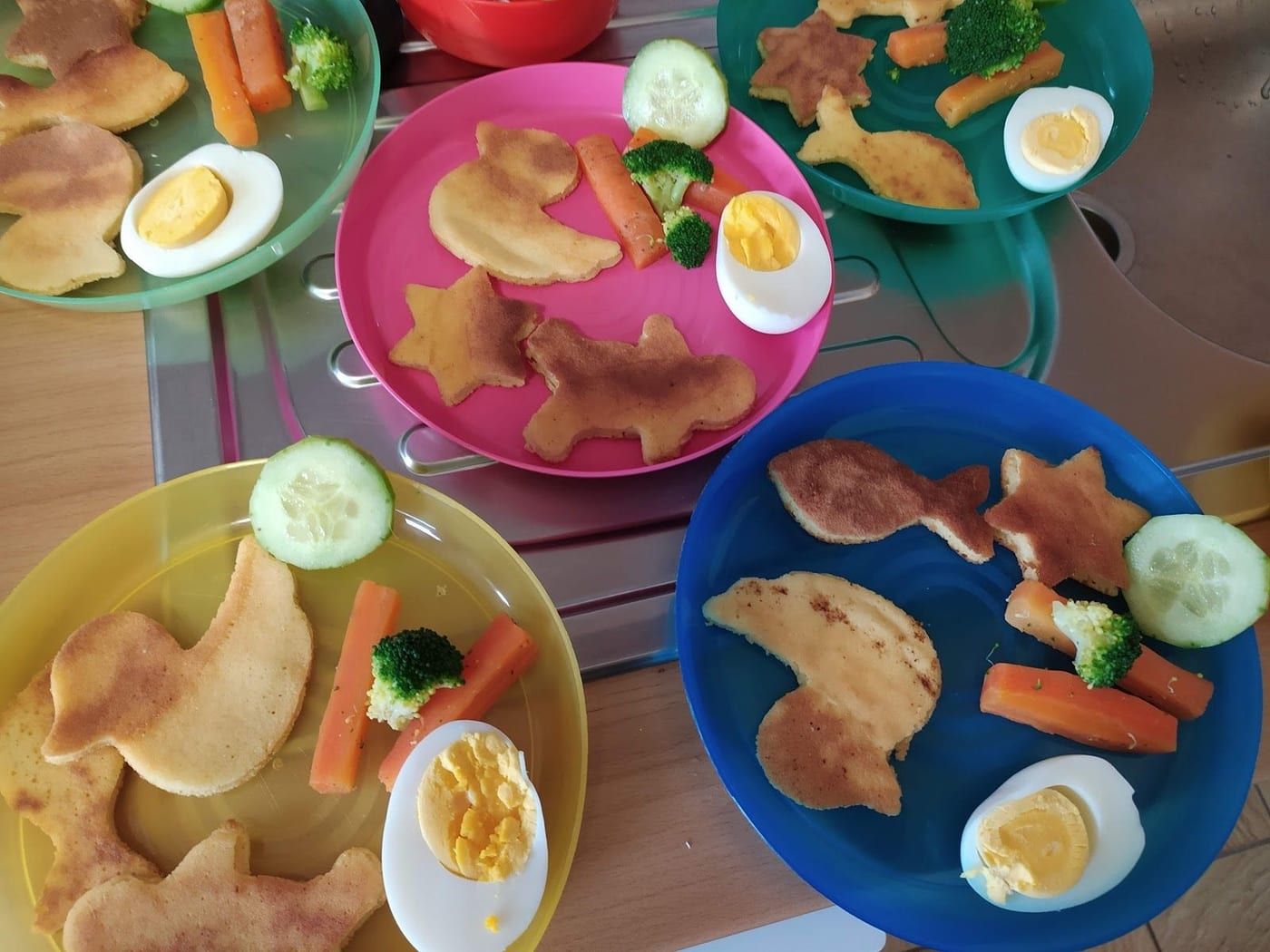 Bunte Kinderteller mit geformten Pfannkuchen und Gemüse