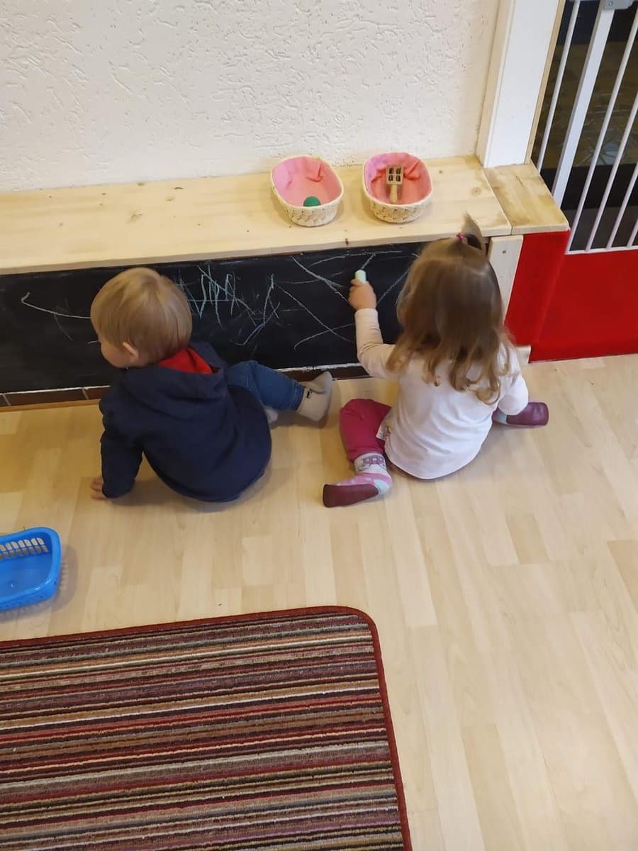 Zwei Kinder von hinten an der Kreidetafel